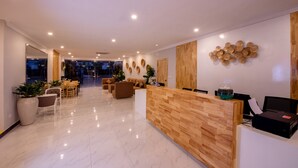 A modern reception area with a wooden reception desk, seating arrangements, and a decorative wall. - Double S Hotel (Battambang)