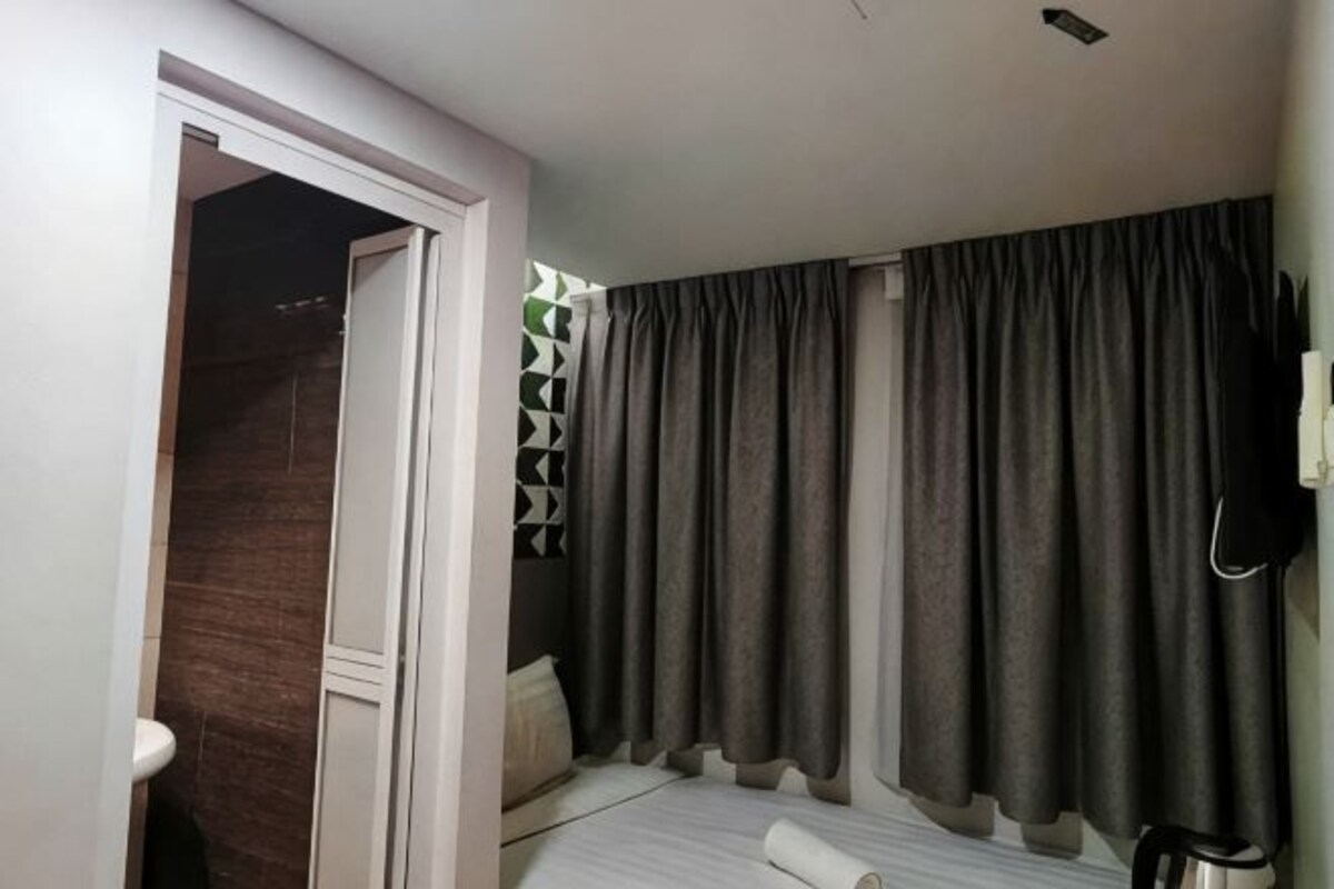 Een slaapkamer met een bed, een deur naar een badkamer en een gordijn.