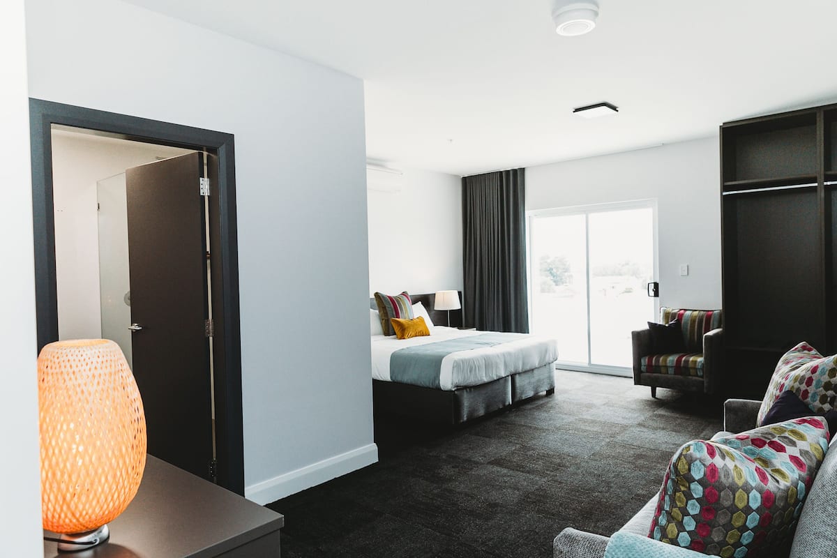 Ein modernes Hotelzimmer mit Bett, Sofa, Lampe und Blick ins Freie.