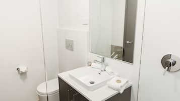 A modern bathroom with a white sink, mirror, and toilet.