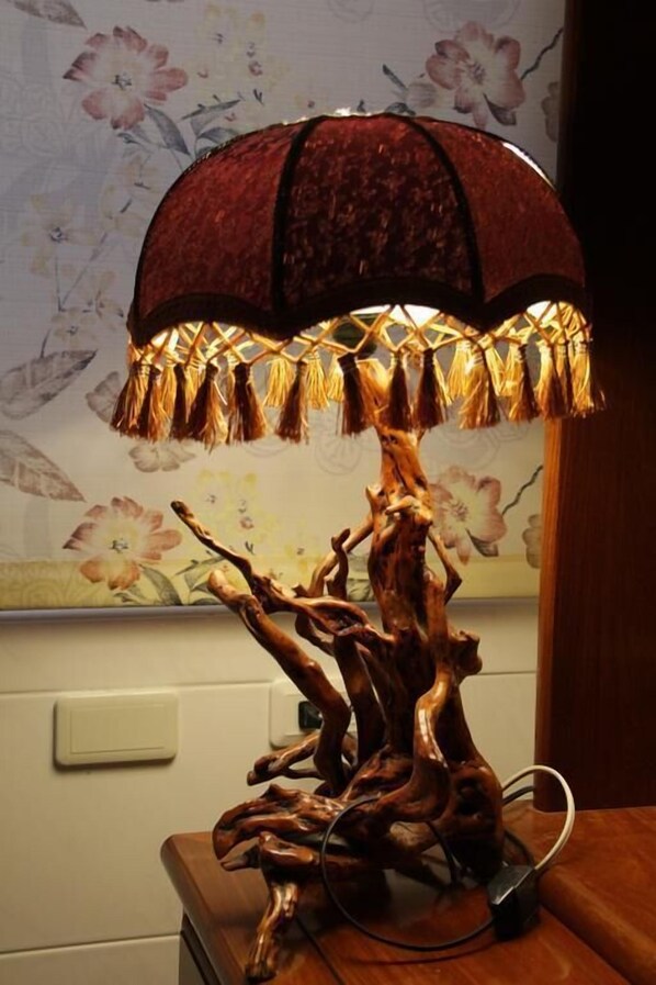 A wooden table lamp with a tree branch base and a red lampshade with tassels. - Heart Stay (Hualien City)