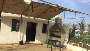 Un patio con una mesa, sillas, una chimenea y un área cubierta.
