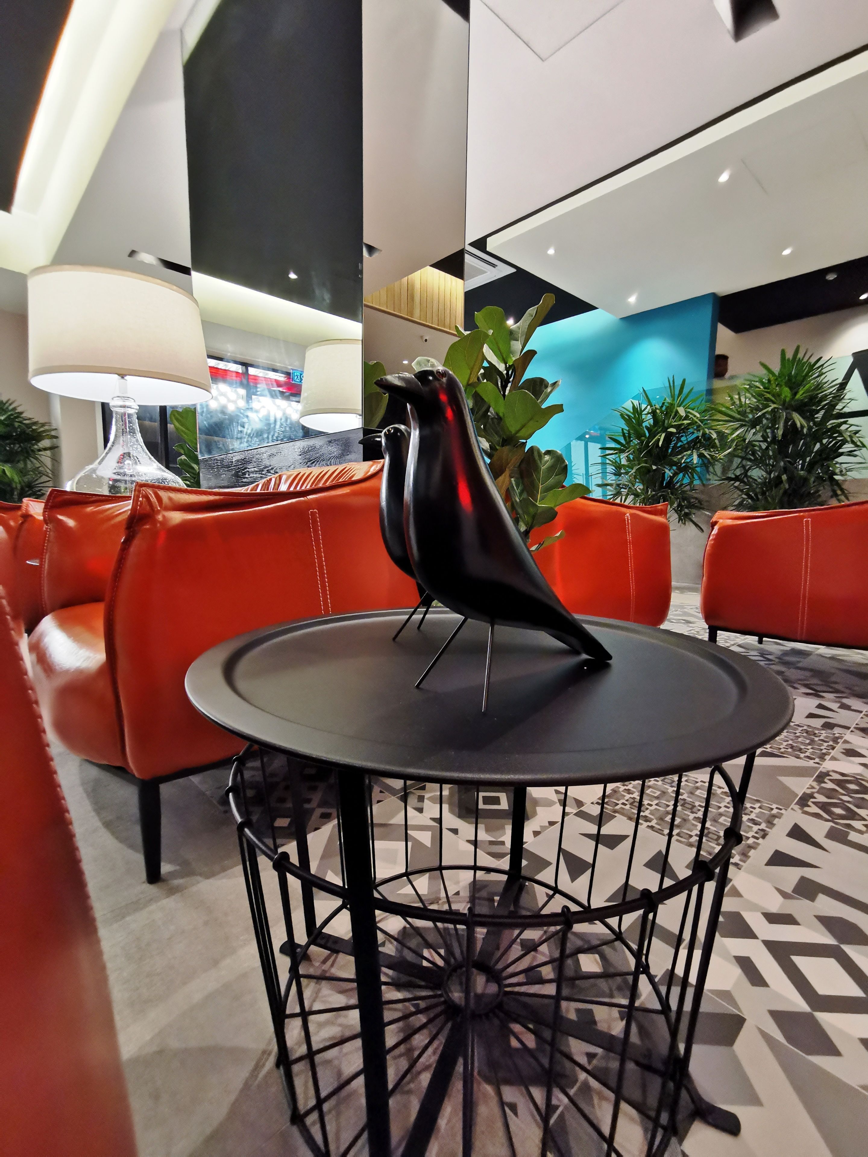 A modern lobby with a round table, red leather seating, and a decorative bird sculpture.