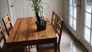 Een eetruimte met een houten tafel, zes stoelen en een potplant.