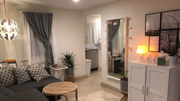 Een moderne woonkamer met een bank, een ronde tafel, een kast en een keuken in de achtergrond.