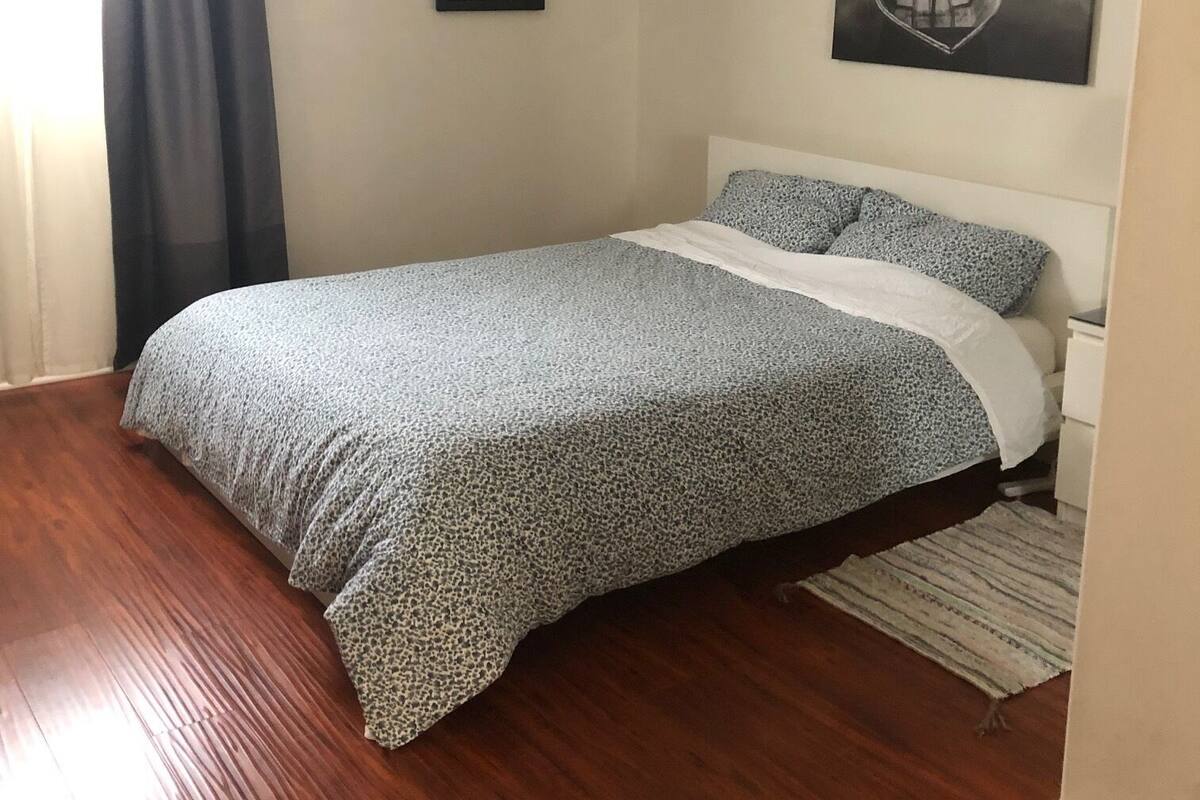 A bedroom with a bed, a framed picture, and a painting on the wall.