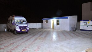 A parking area with a purple van and a small building with a blue roof. - Eden A Park (Palani)