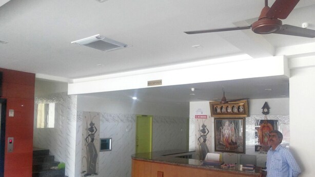 A reception area with a wooden counter, a ceiling fan, and a staircase leading to an upper level. - Eden A Park (Palani)