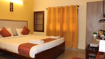 A hotel room with a large bed, a wooden headboard, a desk with a plant, and a curtain.