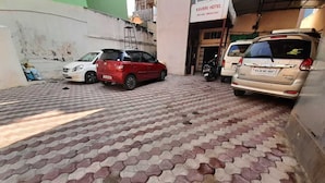 A paved area with cars parked in front of a building labeled "Kaveri Hotel." - Kaveri Hotel (Mysore)