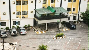A multi-story hotel with a green roof and yellow and white exterior walls, featuring a parking area with several cars. - Londa Hotel (Port Harcourt)