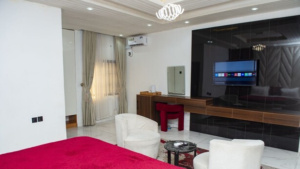 A modern hotel room with a bed, a desk, a TV, and a red chair. - Londa Hotel (Port Harcourt)