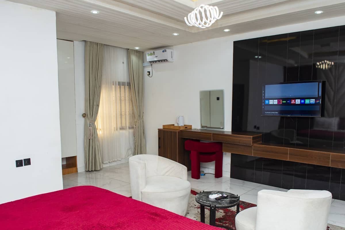 Moderni hotellihuone, jossa on sänky, työpöytä, televisio ja punainen tuoli.