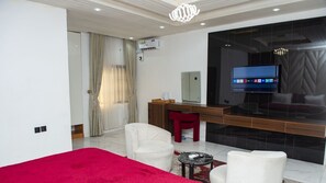 A modern hotel room with a bed, a desk, a TV, and a red chair. - Londa Hotel (Port Harcourt)