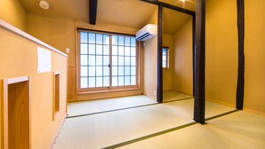 Ein traditioneller japanischer Raum mit Tatami-Boden, einer verschiebbaren Shoji-Türe und einer Deckenleuchte.
