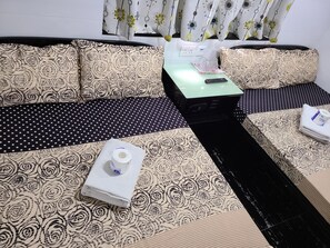 A hotel room with a sofa set, a small table with a remote control, and a neatly folded towel. - Hostel 16 (Kowloon)