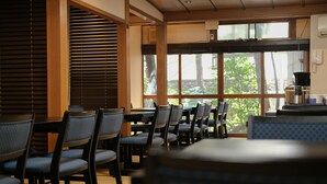 A dining area with wooden tables and chairs, large windows with blinds, and a coffee machine on a counter. - Zenkoji Temple Yakuoin (Nagano)