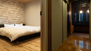 A bedroom with a wooden floor, a bed with white bedding, and a view of a cityscape through a sliding door. - Zenkoji Temple Yakuoin (Nagano)