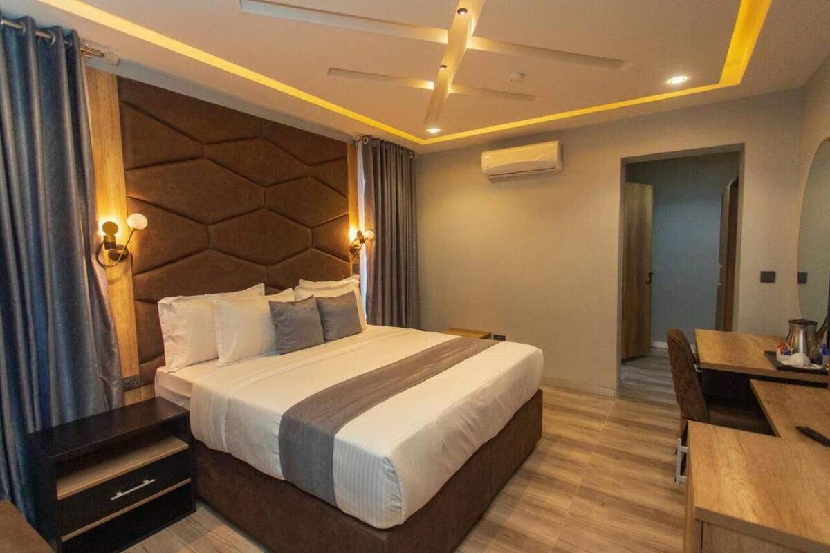 Um quarto moderno com uma cama grande, mesas de cabeceira, uma escrivaninha e uma cadeira.