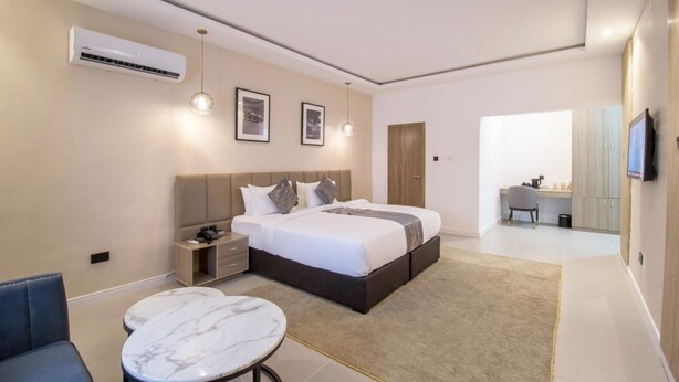 Une chambre d’hôtel moderne avec un grand lit, des tables de chevet, un bureau et une télévision.