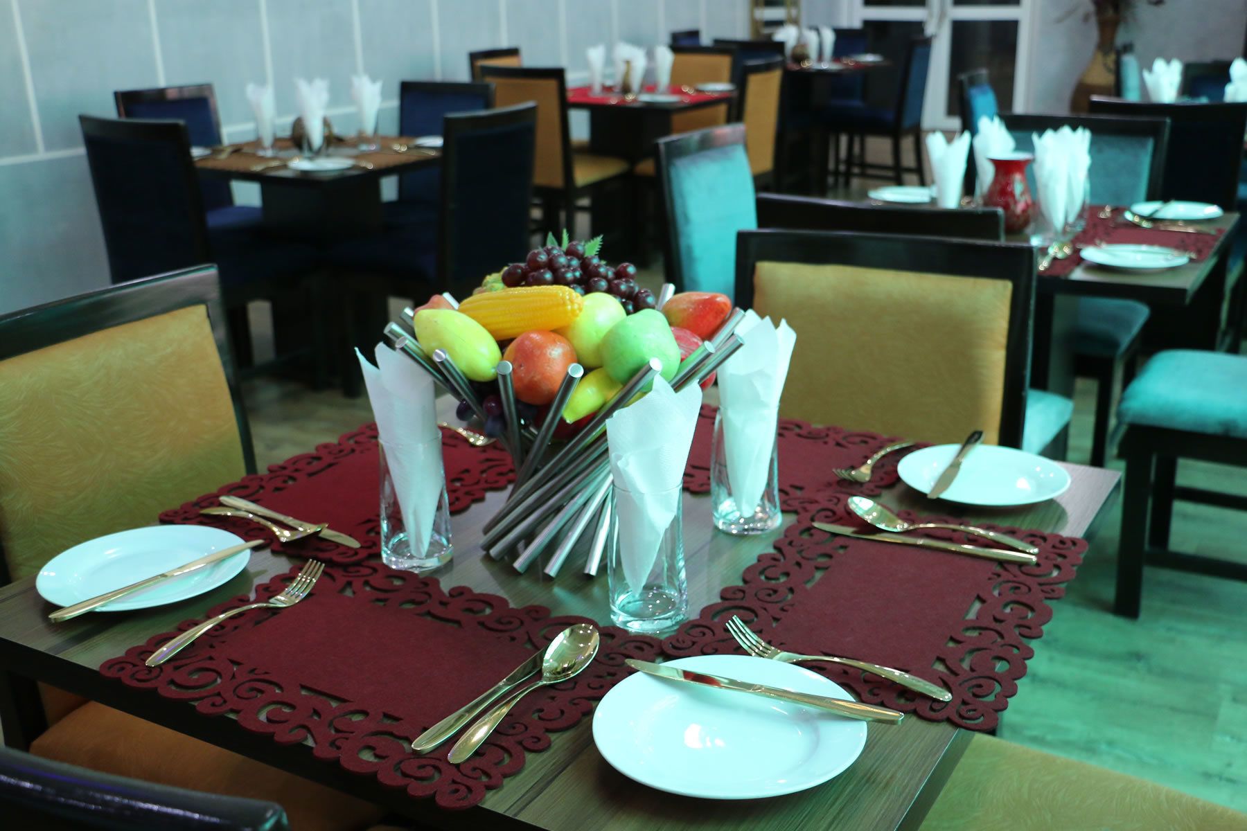 A dining table set with plates, cutlery, and a fruit arrangement.
