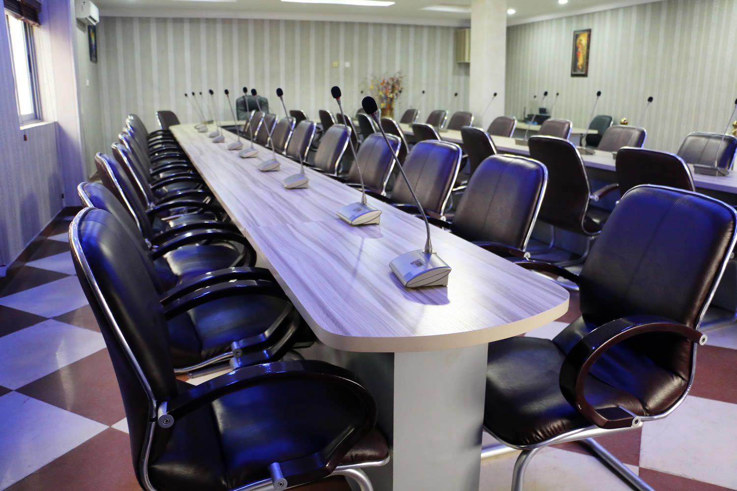 Ein Konferenzraum mit einem langen Tisch, mehreren Stühlen und Mikrofonen.