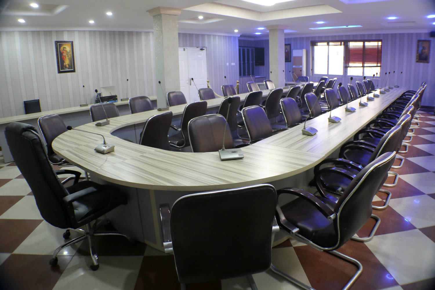 A conference room with a long table, multiple chairs, and a projector screen.