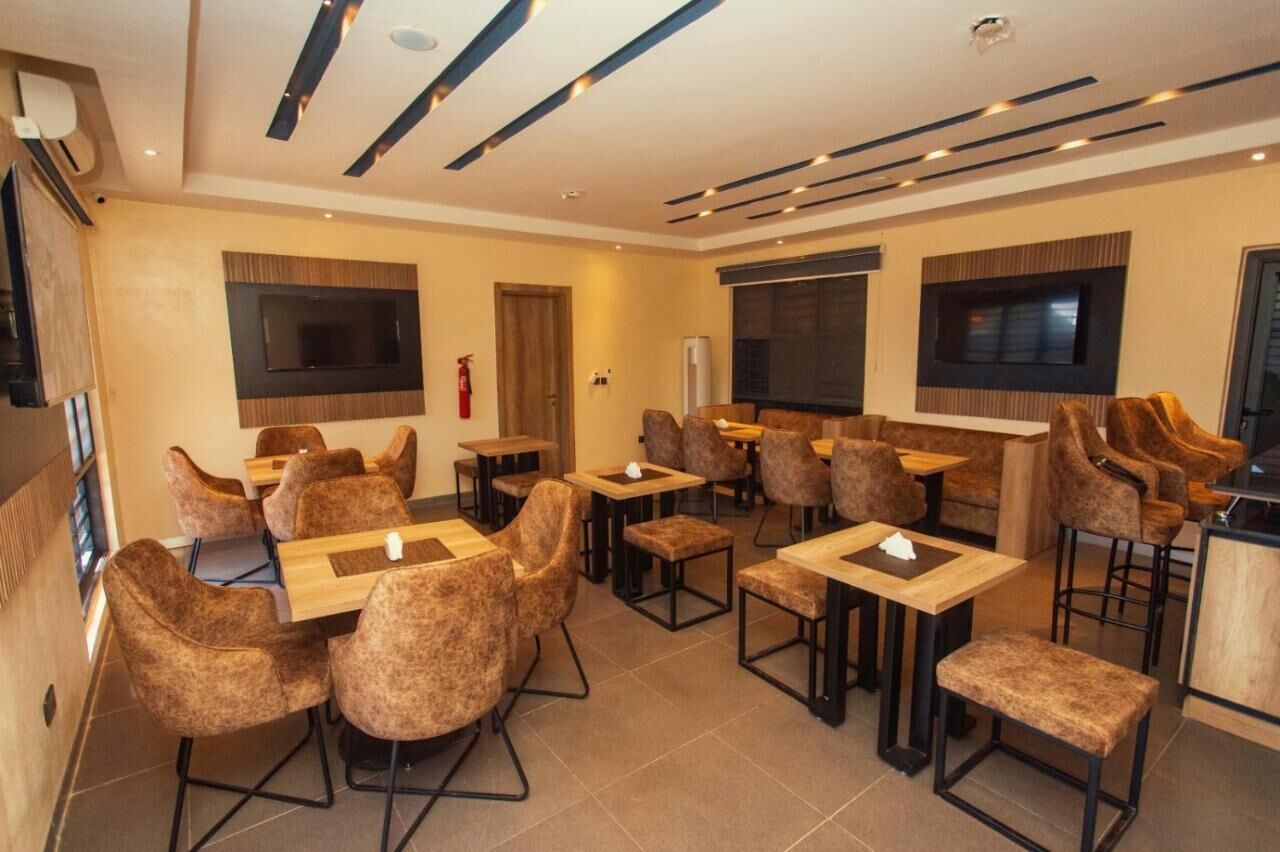 A modern dining area with multiple tables and chairs, recessed lighting, and large windows.