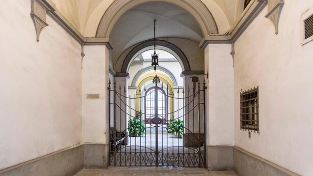 A hallway with a wrought iron gate, arched ceilings, and a hanging light fixture. - B&B Stupido Hotel (Florence)