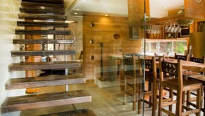 A modern kitchen with a glass staircase, wooden accents, and a dining area with wooden chairs and a table. - Eco Villa Mt Beauty Near Falls Creek & Bright (Tawonga South)