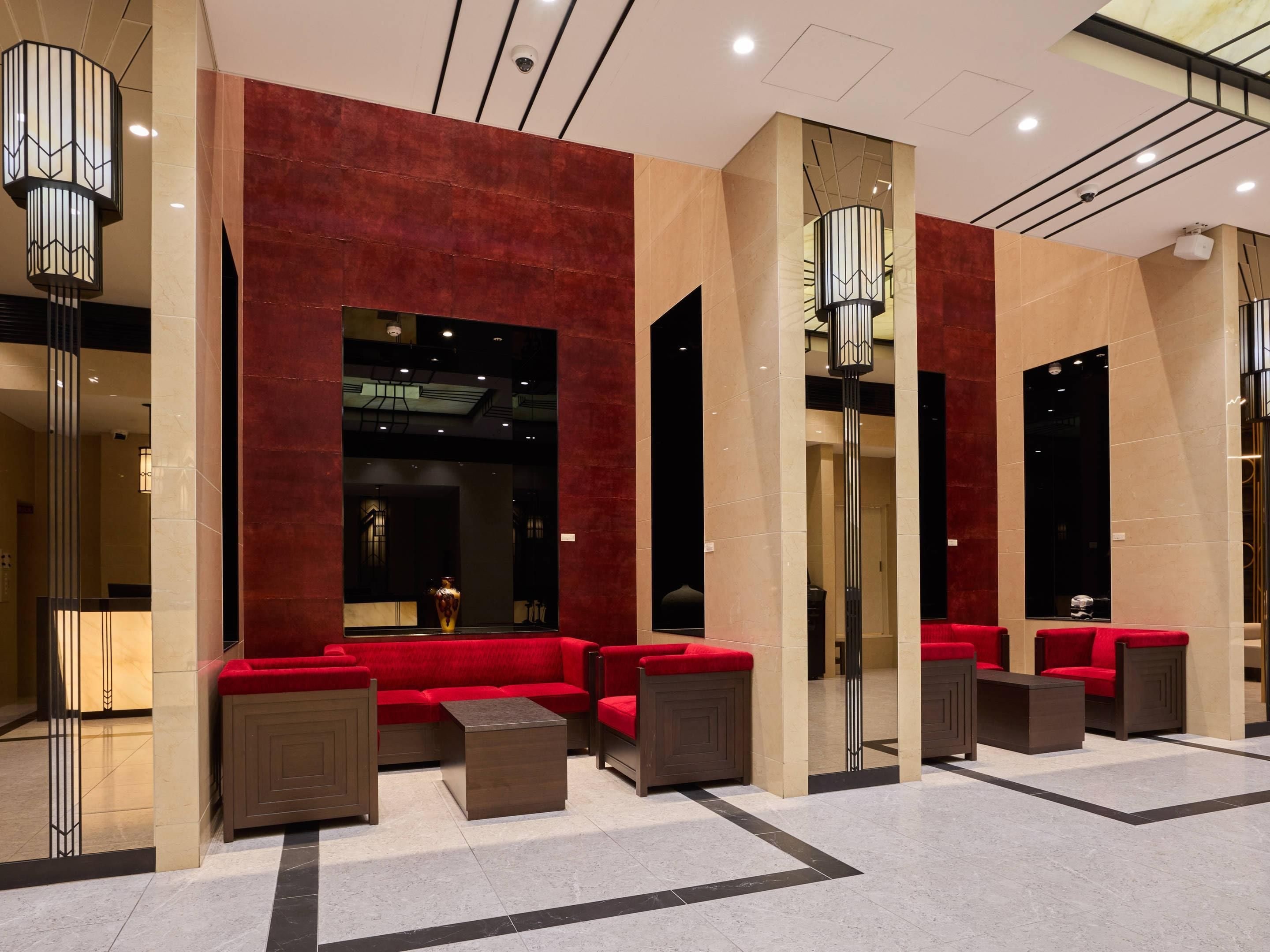 Un hall d’entrée avec des canapés rouges, une colonne centrale et un design moderne au plafond.