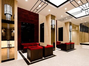 En moderne lobby med højt til loftet, ovenlys og røde siddeområder.