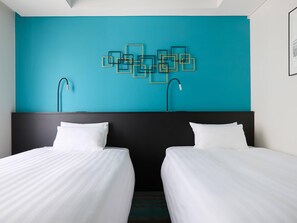 Een hotelkamer met twee bedden, een zwart hoofdeinde, een turquoise accentmuur en een geometrisch kunstwerk aan de wand.