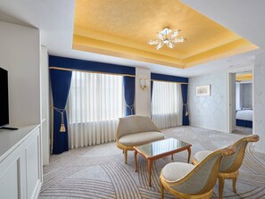 Een hotelkamer met een televisie, twee fauteuils, een salontafel en een plafondlamp.