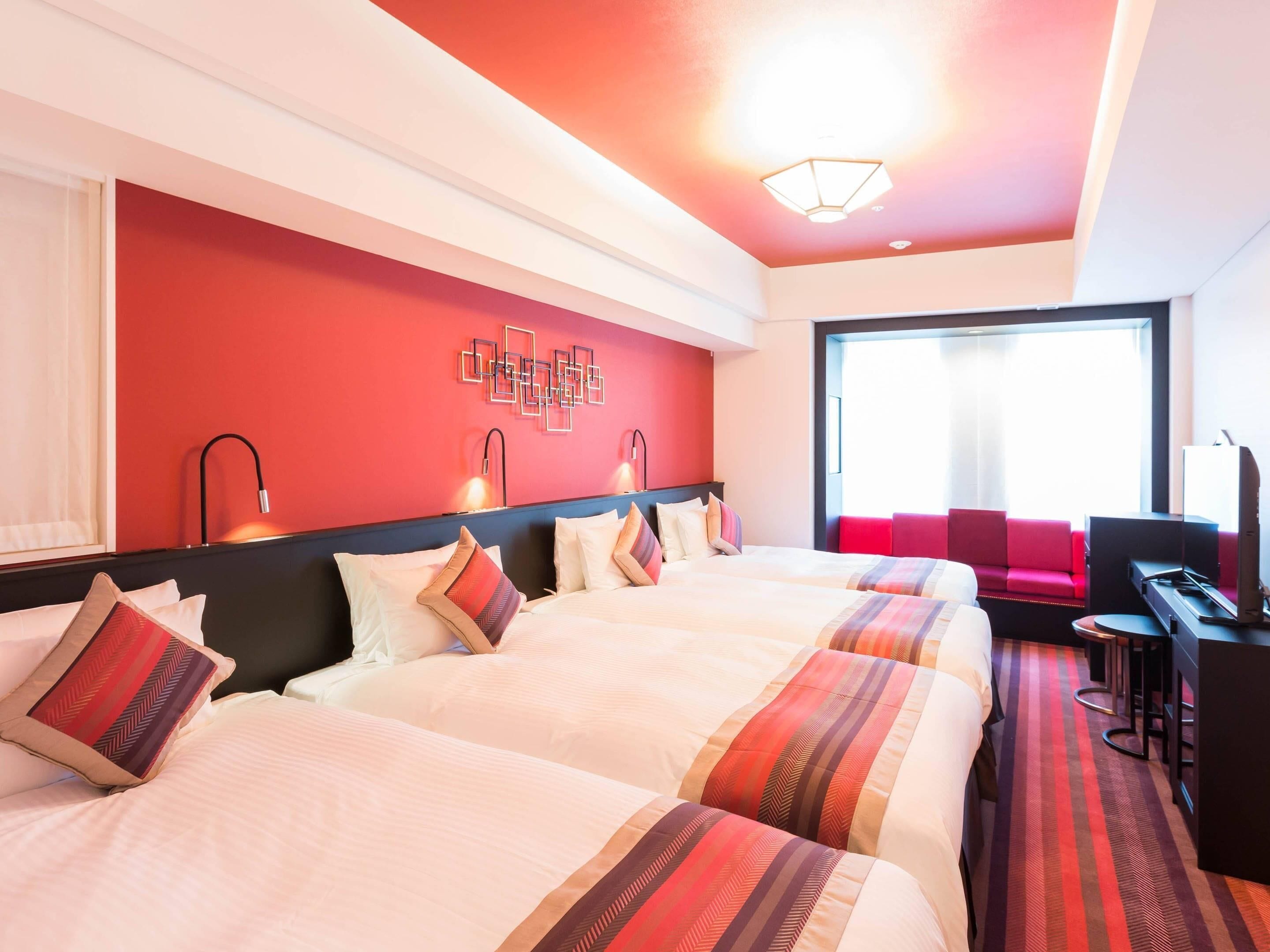 A hotel room with two beds, a desk, a chair, and a large window.