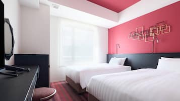A hotel room with two beds, a desk, a mirror, and a window.
