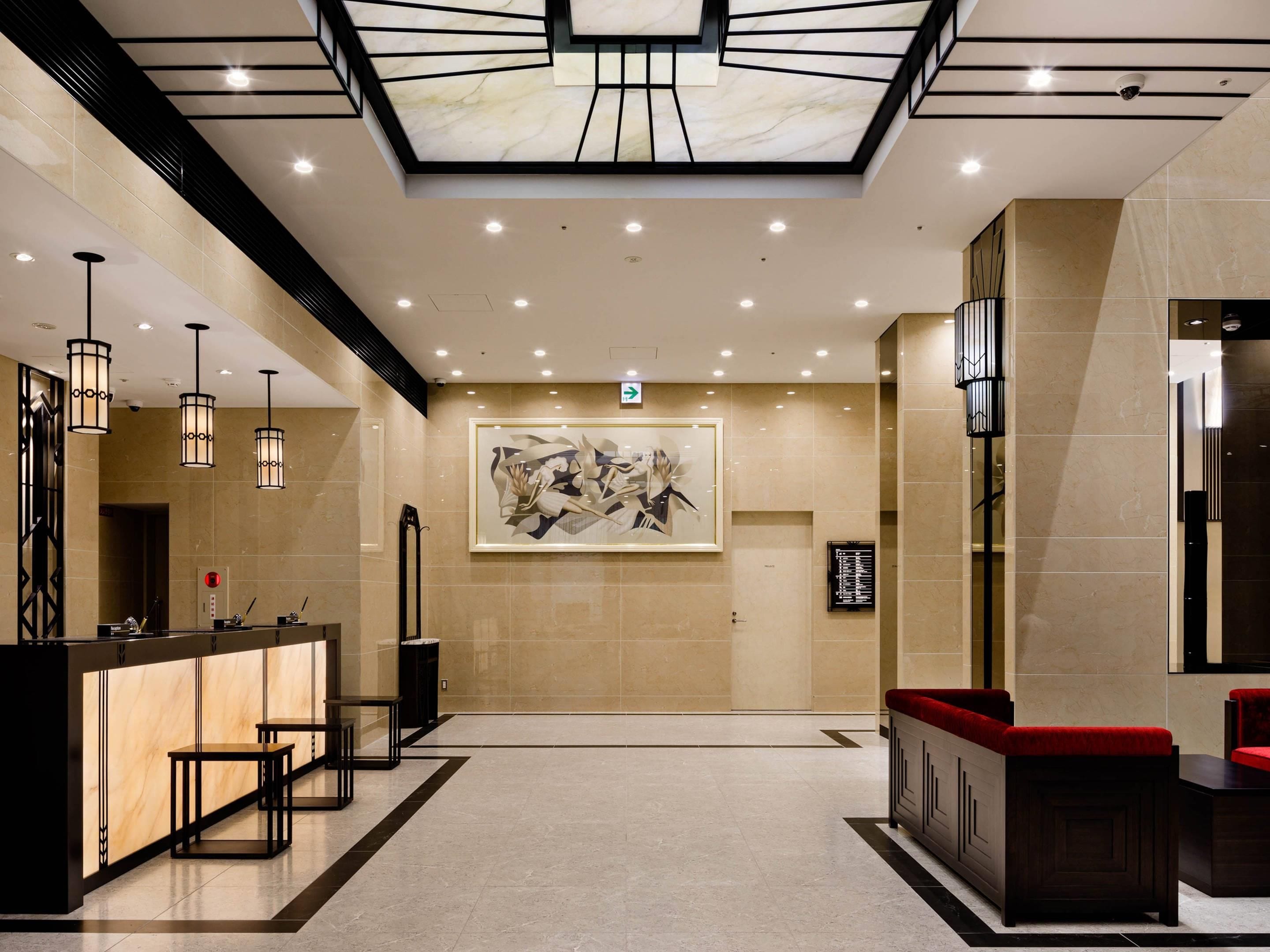 A hotel lobby with a reception desk, seating area, and a large abstract painting on the wall.