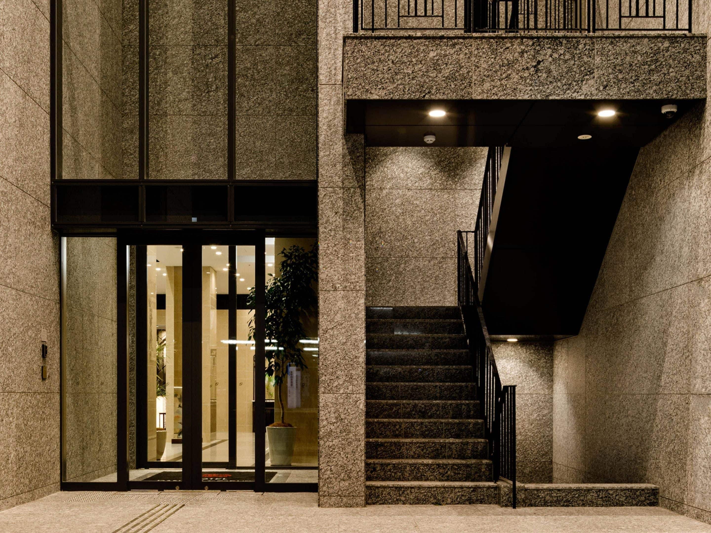 A building entrance with a glass door, a staircase, and a potted plant.