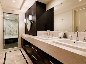 Une salle de bain moderne avec deux lavabos, un grand miroir et une douche à parois de verre.