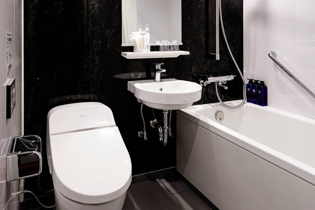 A modern bathroom with a toilet, sink, and bathtub.