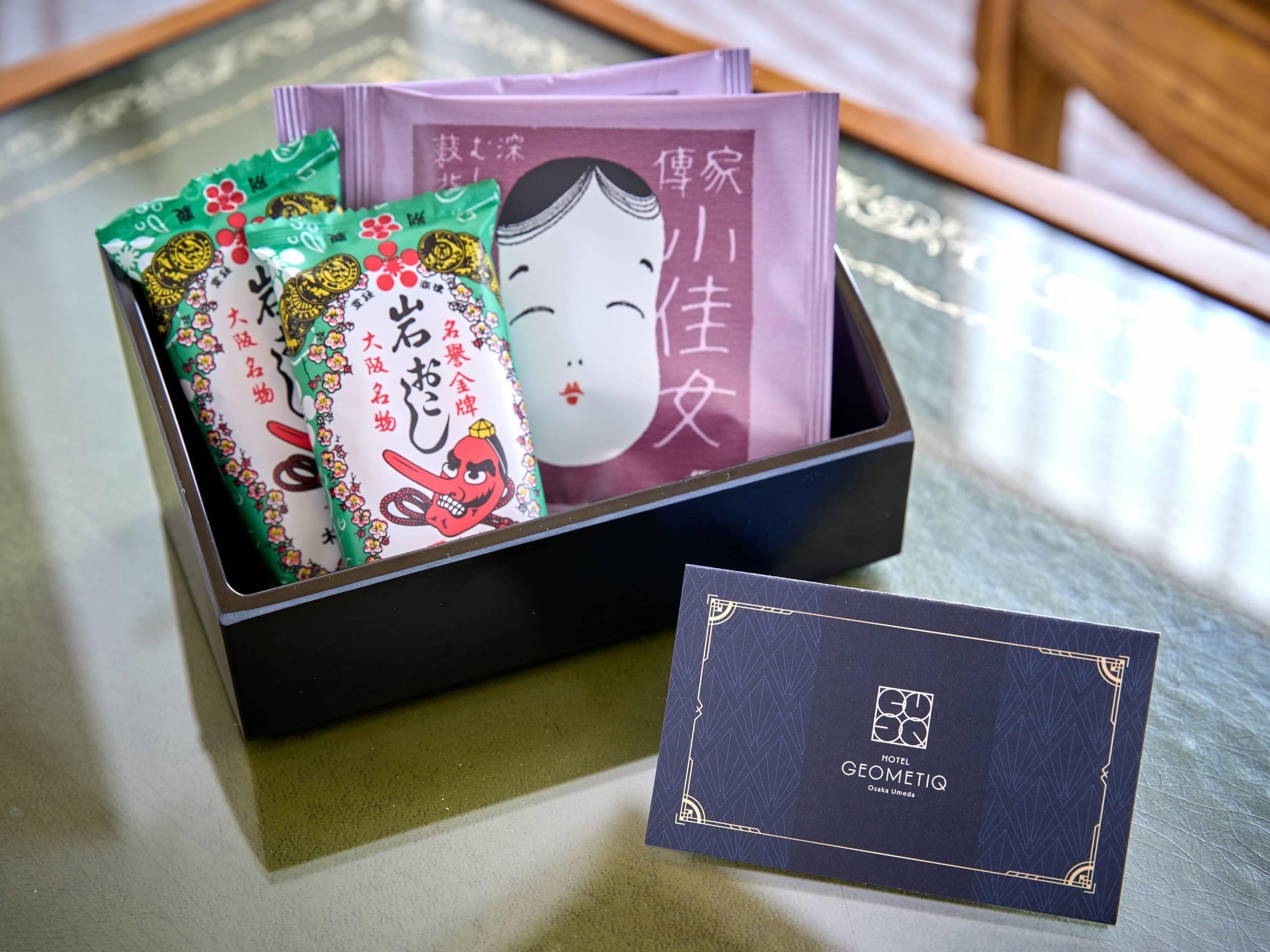 A black box containing several packets with Japanese characters and a card with hotel branding.