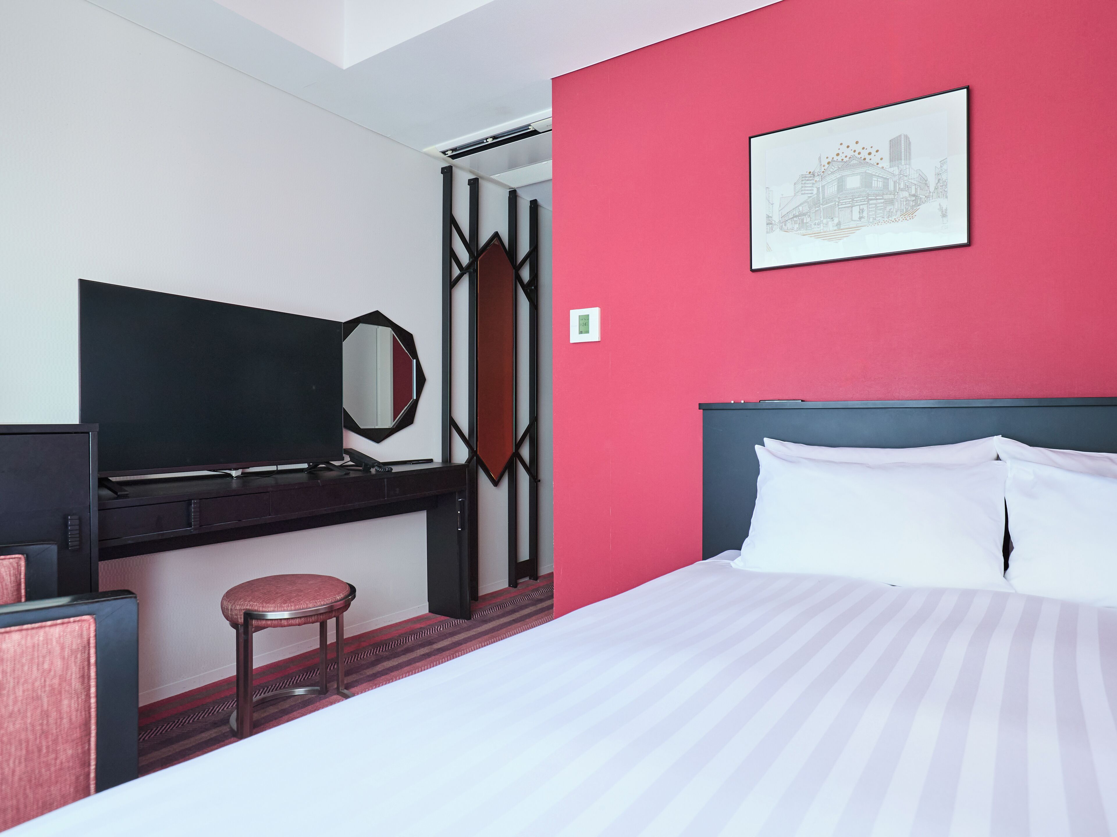 A hotel room with a bed, a desk with a chair, a television, and a mirror.
