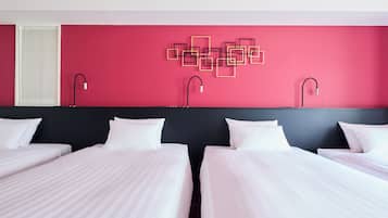 A hotel room with two beds, a red accent wall, and modern wall art.