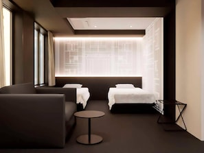 Una habitación de hotel moderna con un sofá, dos camas, una pequeña mesa redonda y una pared con un diseño de luces geométrico.