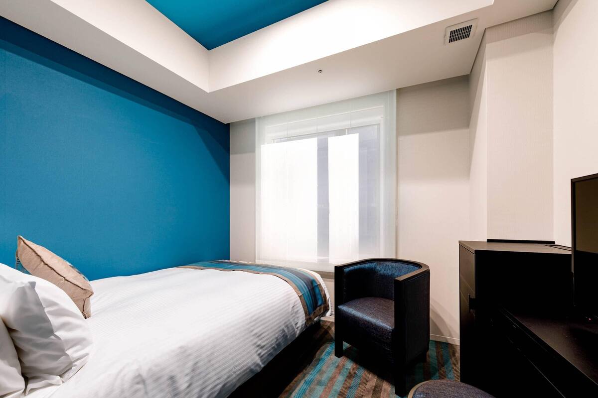 Une chambre d’hôtel avec un lit, une chaise, un bureau et un téléviseur.
