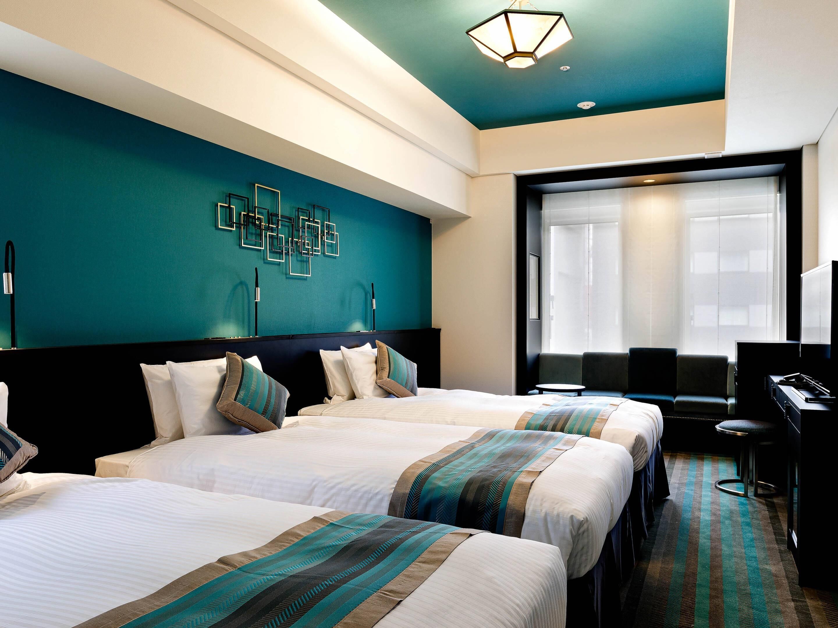 A hotel room with two beds, a desk, a TV, and a large window.