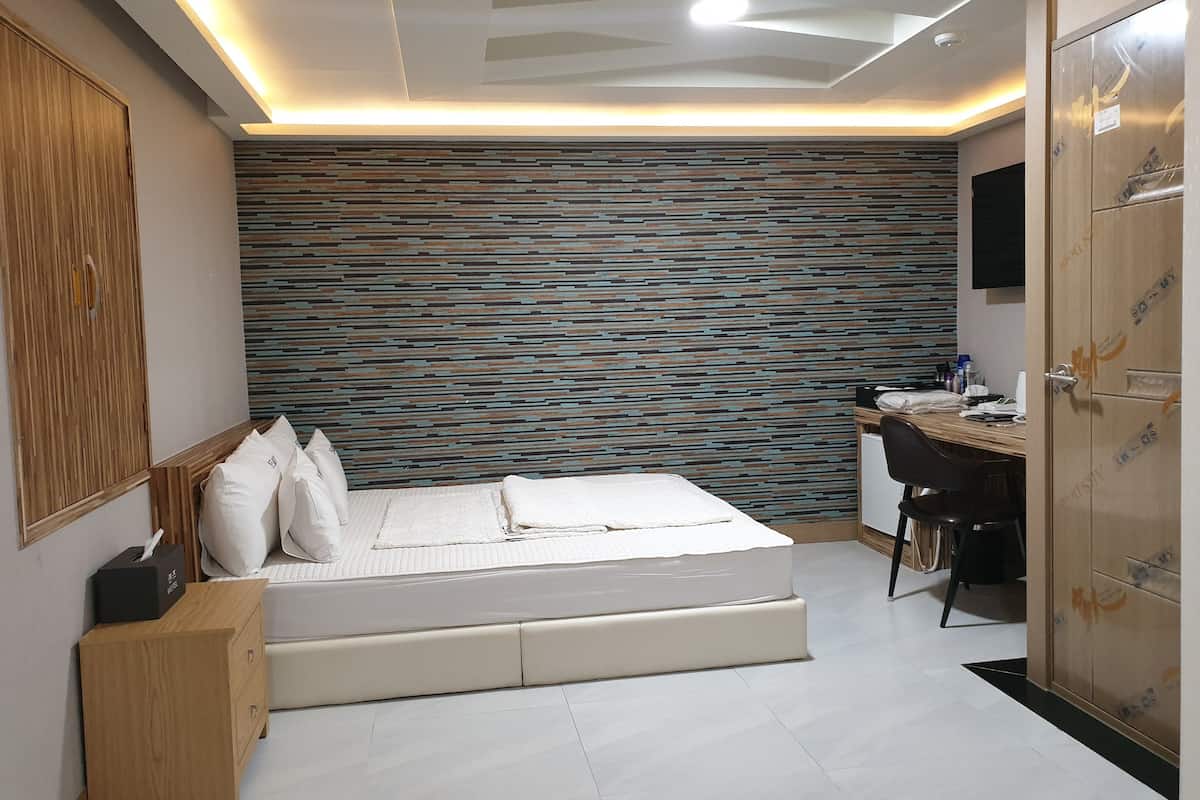 Quarto moderno com cama, mesa de cabeceira e escrivaninha com cadeira.