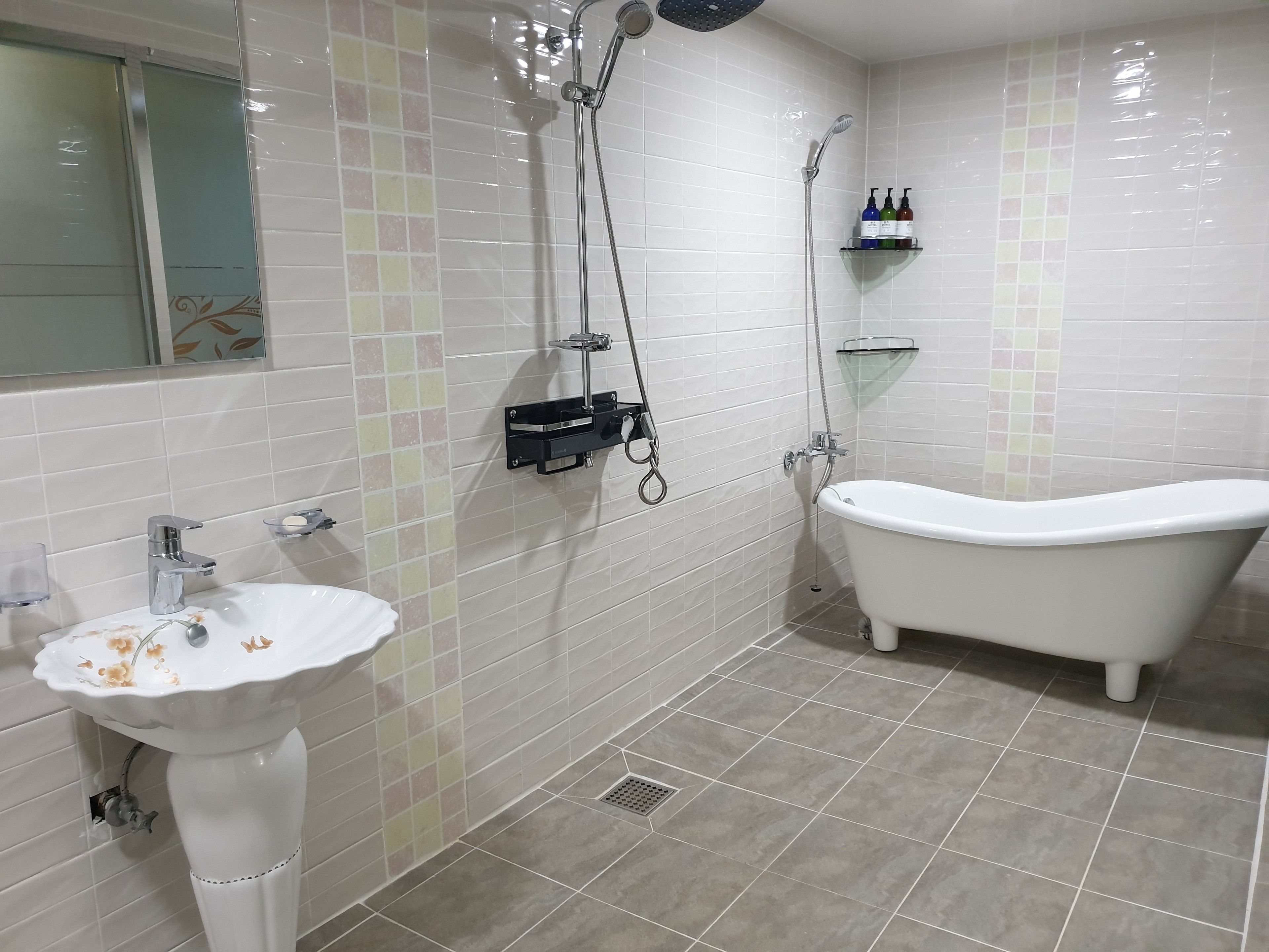 A bathroom with a freestanding bathtub, a pedestal sink, and a shower with a handheld showerhead.