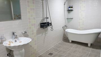 A bathroom with a freestanding bathtub, a pedestal sink, and a shower with a handheld showerhead.