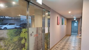 A hallway with patterned floor tiles, glass doors with a nature-themed poster, and a door at the end.